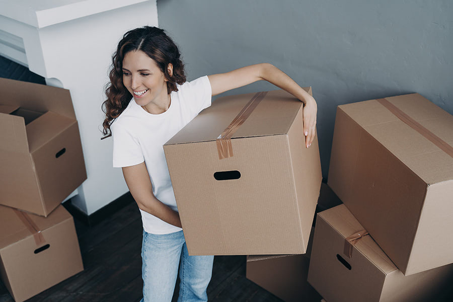 Happy girl with a box in her hand, moving into a new apartment.