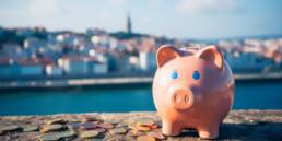 Cost of Living in Portugal Compared to the US 31 Piggy bank with backdrop of a Portuguese city