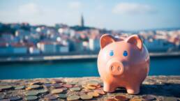 Cost of Living in Portugal Compared to the US 26 Piggy bank with backdrop of a Portuguese city